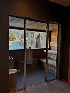 een glazen deur die leidt naar een badkamer met een bad bij Hotel Maso del Brenta in Caderzone