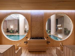 a wellness room with a pool and a circular mirror at Swissôtel Tbilisi in Tbilisi City
