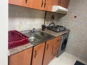una cucina con lavello e lavatrice di DELUXE Studio Apartment a Sharjah