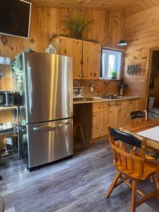 eine Küche mit einem Kühlschrank aus Edelstahl und einem Tisch in der Unterkunft Le Richelieu in St-Bernard de Lacolle