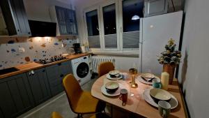 een keuken met een houten tafel met stoelen en een kerstboom bij Apartament Granatowy Chill in Łódź