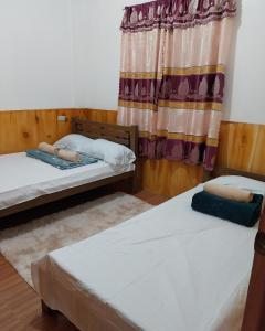twee bedden in een kamer met een raam bij Ag-agongan Lodge in Baguio