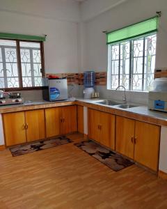 een keuken met houten kasten, een wastafel en 2 ramen bij Ag-agongan Lodge in Baguio