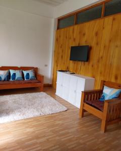 een woonkamer met een bank en een tv aan de muur bij Ag-agongan Lodge in Baguio