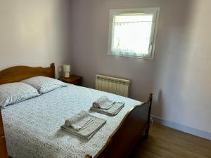 een slaapkamer met een bed met handdoeken en een raam bij Maisonnette deux couchages in Chantenay-Saint-Imbert