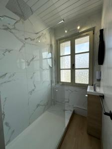 ein Bad mit einer Dusche und weißen Marmorwänden in der Unterkunft Spacieux studio rénové en centre ville - Apt7 in Givet + 9 Fotos