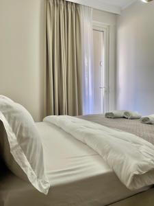 una camera da letto con due letti con lenzuola bianche e una finestra di Villa Safira a Durrës