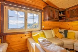 a living room with a couch and two windows at Chalet Mazze in Bettmeralp