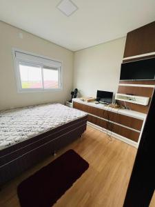 a bedroom with a bed and a desk with a laptop at Casa condomínio lagoa cortada in Balneário Gaivotas