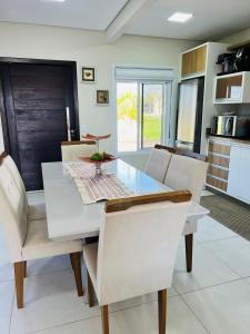 una sala da pranzo con tavolo e sedie bianchi di Casa condomínio lagoa cortada a Balneário Gaivotas