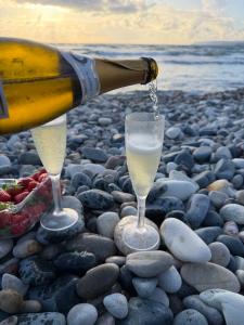 Een fles champagne die in twee glazen wordt geschonken op een rotsachtig strand. bij Villa Arfa in Peyia