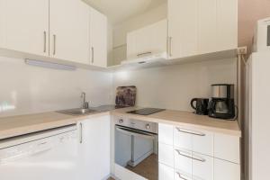 a white kitchen with white cabinets and a sink at Les Orres Plein Sud - Studio avec balcon in Les Orres