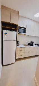 a kitchen with a white refrigerator and a microwave at Apartamento perto da Praia em Itapema!!! in Itapema