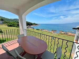 een balkon met een tafel en stoelen en de oceaan bij Résidence Punta paliagi in Calcatoggio
