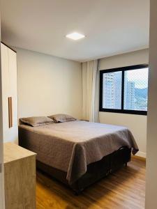 a bedroom with a bed and a large window at Apartamento perto da Praia em Itapema!!! in Itapema +21 photos