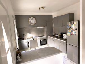 a kitchen with a refrigerator and a clock on the wall at La 1848 Narbonnaise in Narbonne
