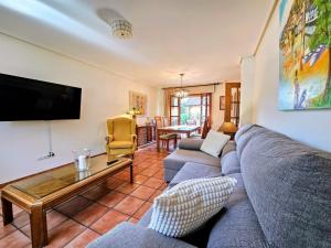 een woonkamer met een bank en een tv bij Villa Freya - Casa con jardín cerca de la playa in Las Conchas