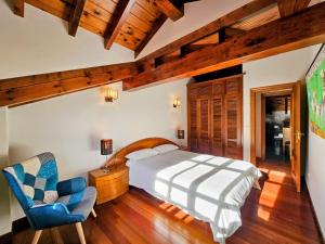 een slaapkamer met een bed en een stoel bij Villa Freya - Casa con jardín cerca de la playa in Las Conchas