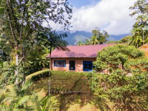 een huis met een rood dak in een bos bij Sitio Dona Bela - Rio da Prata in Joinville