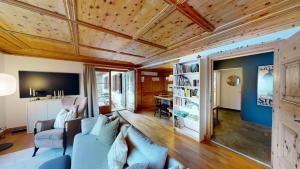 un soggiorno con divano blu e soffitti in legno di Apartment Pradatsch a Celerina