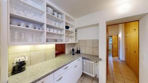 una cucina con armadi bianchi e un corridoio di Apartment Pradatsch a Celerina