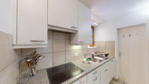 una cucina con mobili bianchi e un lavandino di Apartment Pradatsch a Celerina Altre 6 foto