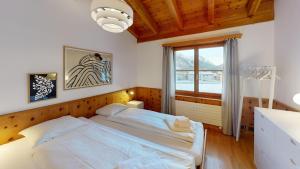 una camera da letto con un grande letto bianco e una finestra di Apartment Pradatsch a Celerina