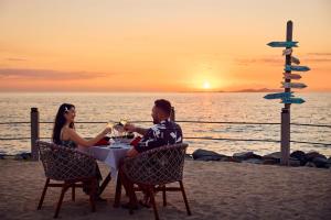 Ein Mann und eine Frau sitzen bei Sonnenuntergang an einem Tisch am Strand. in der Unterkunft Radisson Blu Resort Fiji in Denarau