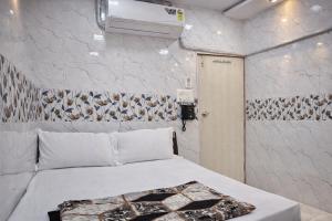 a bedroom with a white bed and a wall at Relax Hotel Kurla in Mumbai
