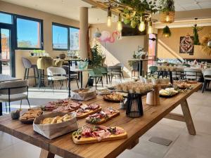 ein langer Holztisch mit vielen Tellern voller Essen darauf in der Unterkunft Aparthotel Adagio Access Porte de Camargue in Saint-Martin-de-Crau
