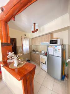 a kitchen with a table and a refrigerator at Apart Hotel Rústicos Valentina in Dolores