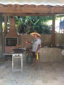een man met een strohoed staat voor een barbecue bij Casa na mata ceu iluminado in Guararema