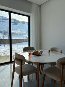 a dining room with a table and chairs and a window at Shahdag S&R House in Qusar