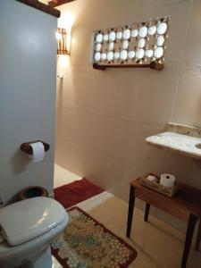 a bathroom with a toilet and a sink and a table at Campo das Margaridas Santo Andre in Santo André