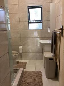 a bathroom with a sink and a toilet and a window at Unit 5 Manzini Chalet in St Lucia