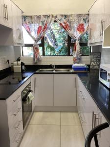 a kitchen with white cabinets and a sink and a window at Unit 5 Manzini Chalet in St Lucia +13 photos