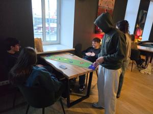 een man die naast een tafel staat met een groep mensen bij Hedgehogs backpackers hostel in Rīga
