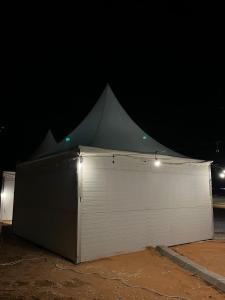 ein großes weißes Gebäude mit einem Zelt im Dunkeln in der Unterkunft خيم مبيت ملكية بالصياهد in Rumāḩ