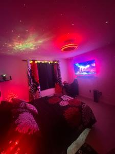una camera da letto con illuminazione rosa e un letto con televisione di Japanese Theme Private Suite a Suffolk