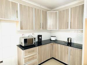 a kitchen with wooden cabinets and a microwave at Asamez Apartments in Lilongwe