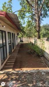 a porch of a house with a tree and stairs at Aarex 63B Sparsh Chalet in Dhamni