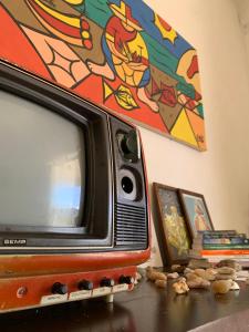 een televisie die op een tafel staat met een schilderij ernaast bij FLOR DE ARUANDA - Hostel e Acampamento in Cabo de Santo Agostinho +16 foto's