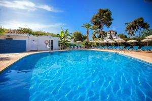 a large blue swimming pool with chairs and umbrellas at Hotel Servigroup Romana in Alcossebre