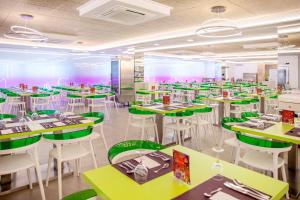 een restaurant met groene tafels en witte stoelen bij Hotel Servigroup Romana in Alcossebre