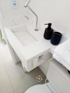 een witte badkamertafel met een wastafel en handdoeken bij Aconchego do mar II in Rio das Ostras