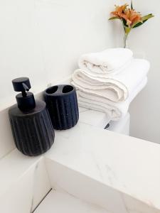 een badkamer met twee zwarte handdoeken en een vaas met bloemen bij Aconchego do mar II in Rio das Ostras +21 foto's