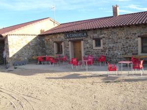 a building with red chairs and tables in front of it at La Candela in Rabanal del Camino