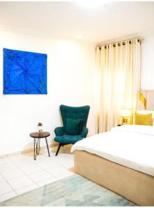 een slaapkamer met een bed en een blauwe stoel bij Bito luxury - Wuse ll in Abuja