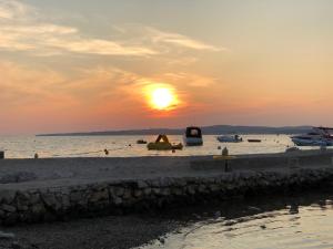 a sunset on a beach with boats in the water at Apartman a tengernél in Vir