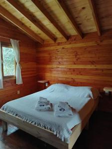 une chambre avec un lit dans une cabane en rondins dans l'établissement El Estribo, à Lago Puelo